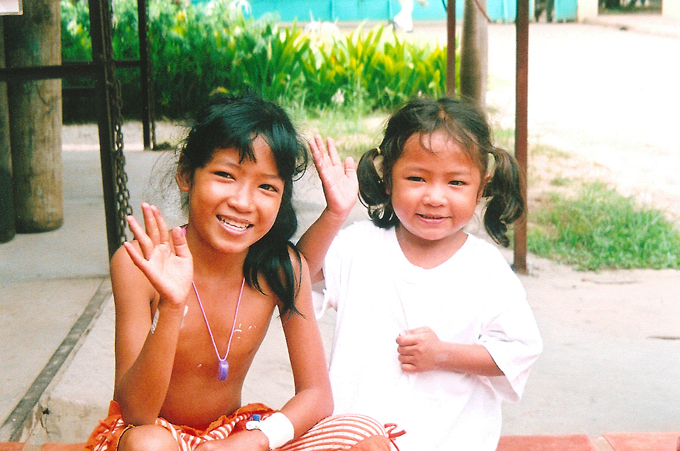 Two young girls wave at the camera.
