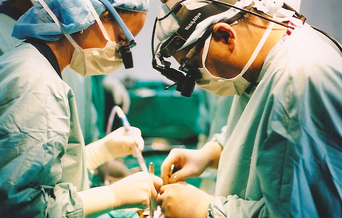 Two surgeons performing surgery on a patient in an operating room.