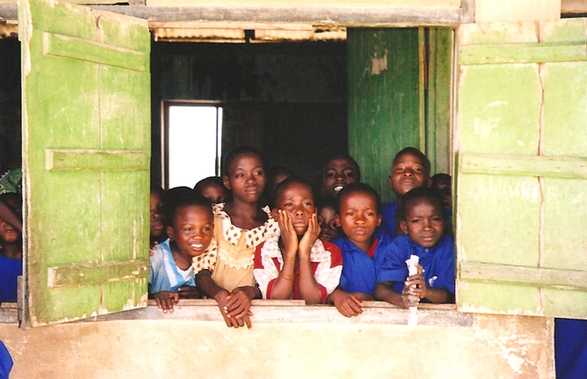 A group of children sitting in front of a window.